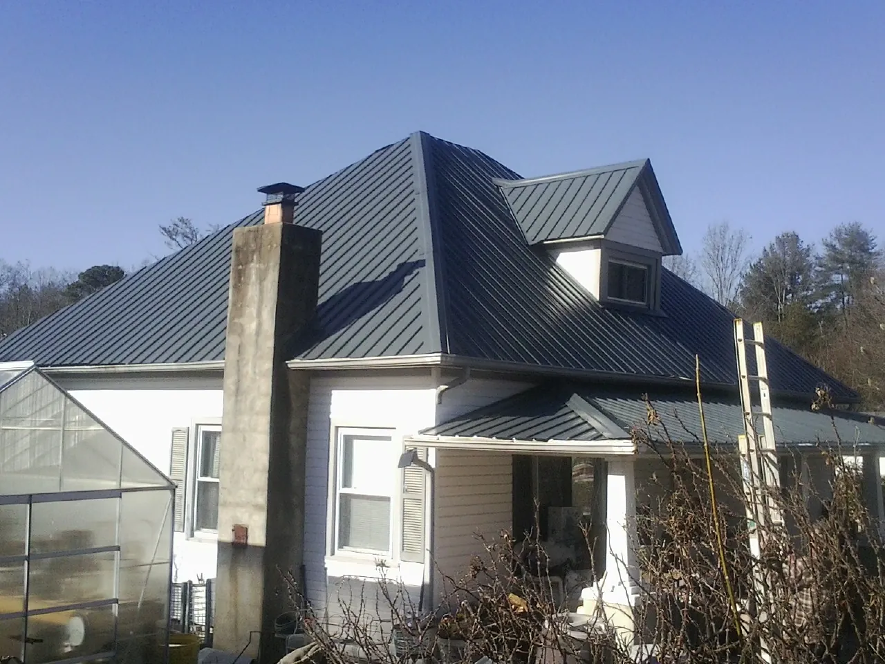 Dark blue standing seam metal roof on a white farmhouse with dormer — Slate & Tile Roof Repair by Roofing Brothers in Wallington