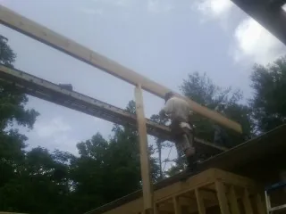 Carpenter setting a ridge beam over a new addition frame — Ice Dam Removal by Roofing Brothers in Wallington