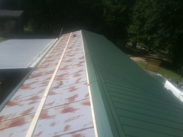 Old rusted panels beside newly installed green metal roofing — Wind Damage Roof Repair by Roofing Brothers in Wallington