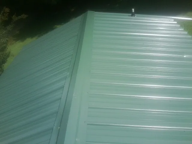 New green metal panels meeting at the ridge of a roof — Flat Roof Repair work by our crew in Wallington