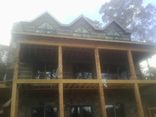 Dormers and porch framing on a large log home under construction — Roof Coating work by our crew in Wallington