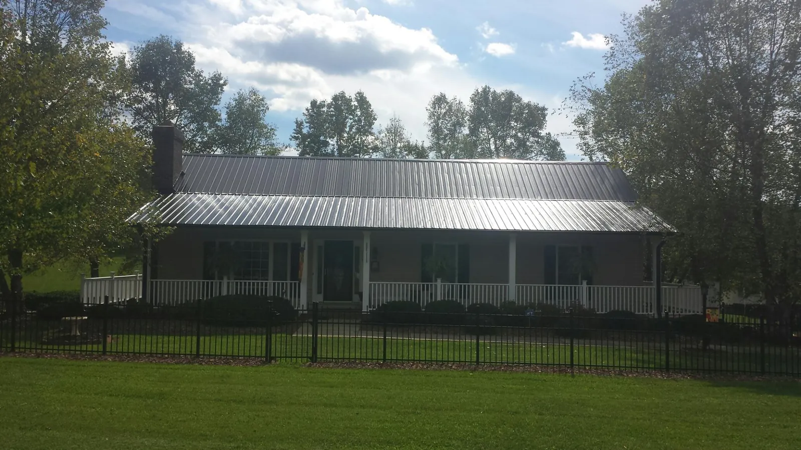 Gray metal roof on a brick ranch with a full width front porch — Gutter Guard Installation work by our crew in Wallington