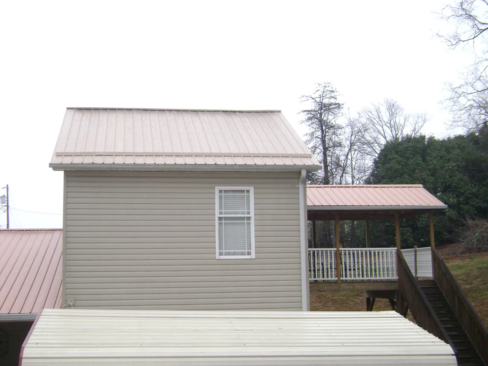 Tan metal roofs on a two story addition and attached porch, from a Roof Replacement job in Wallington